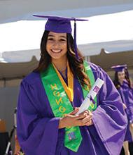 圣胡安大学毕业生，身穿紫袍绿衫，对着镜头偷偷微笑